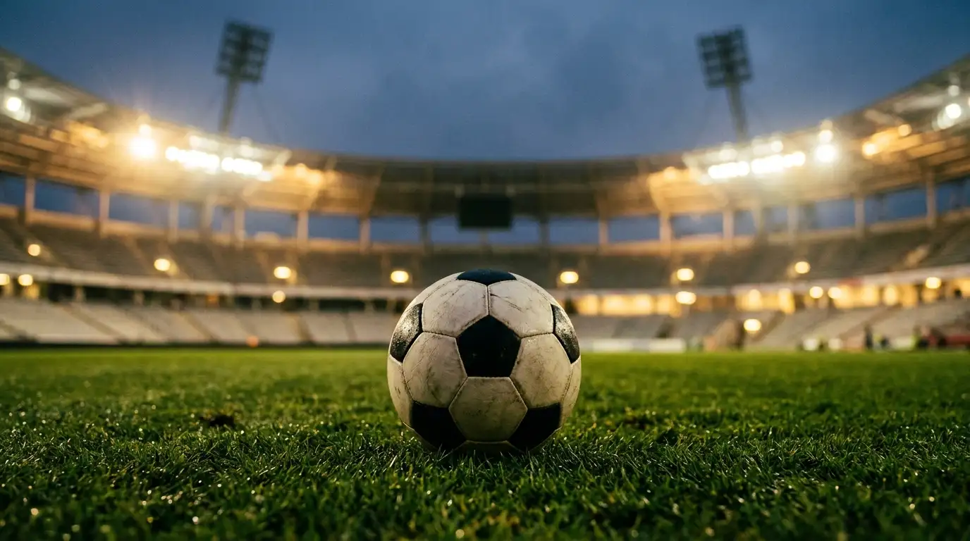Detail futbalovej lopty na trávniku pod reflektormi večerného štadióna pred výkopom